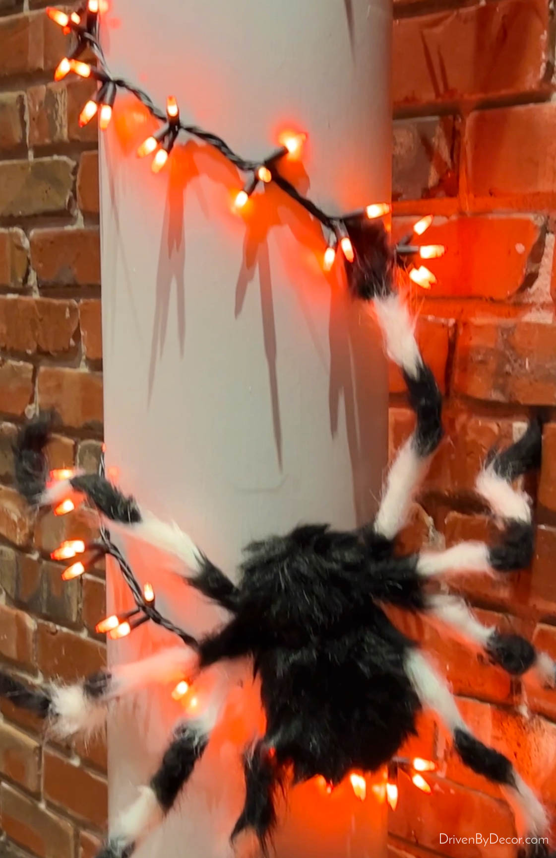 Hairy spiders and orange string lights on porch columns for Halloween