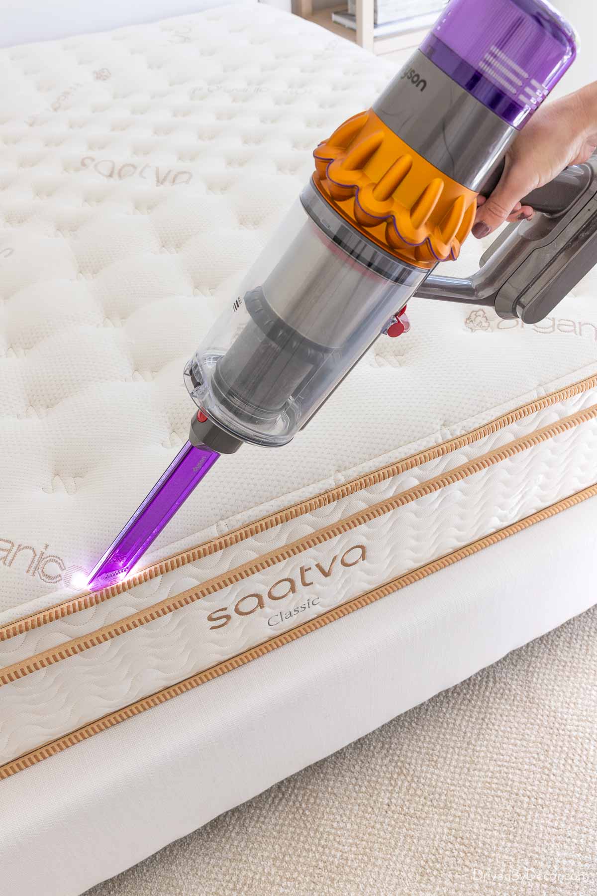 Vacuuming edges of mattress with the crevice tool on a handheld vac