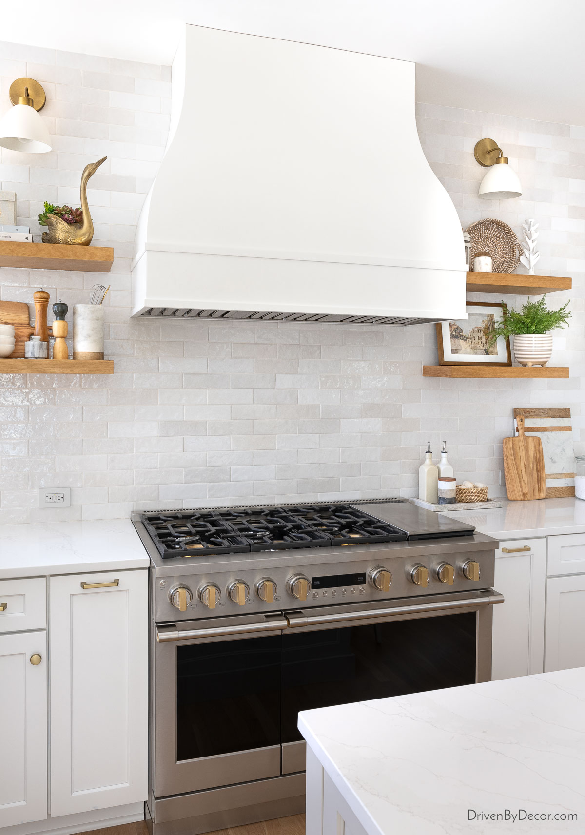 Área de cocina y capucha en forma de campana con estantes de madera flotante y luces de pared